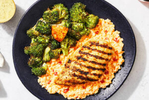 Plated Factor modified keto meal grilled chicken breast with grits and broccoli